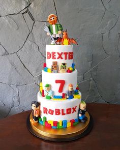 a three tiered cake decorated with legos and characters on it's sides