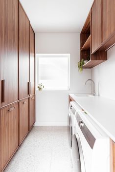 a washer and dryer in a room with wooden cabinets on the wall, and a window