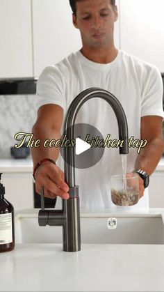 a man standing in front of a kitchen sink pouring something into a glass cup with the words, the coolest kitchen tap