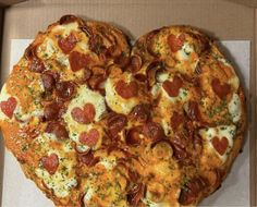 a heart shaped pizza in a box with pepperoni and cheese toppings on it