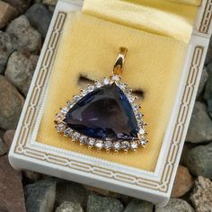 This gorgeous pendant is centered with a triangle cut iolite in a three-prong chevron setting. The center is surrounded by a halo, prong set with twenty-seven (27) round brilliant cut diamonds. The pendant measures 32.9mm long, including the hinged and locking bail, by 29.0mm wide and 8.9mm deep. This pendant does not include a chain. Elegant Formal Jewelry With Trillion Cut, Elegant Jewelry For Formal Occasions With Trillion Cut, Classic Tanzanite Jewelry In Trillion Cut, Trillion Cut Sapphire Jewelry, Elegant Tanzanite Jewelry With Trillion Cut, Elegant Trillion Cut Tanzanite Jewelry, Formal Jewelry With Trillion Cut Halo Setting, Formal Trillion Cut Jewelry With Halo Setting, Formal Fine Jewelry With Trillion Cut