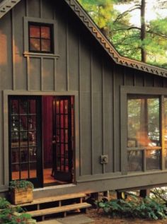 a small house with lots of windows in the woods