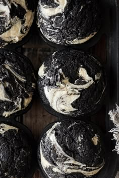 chocolate cupcakes with white frosting and oreo cookies in the middle on a black tray