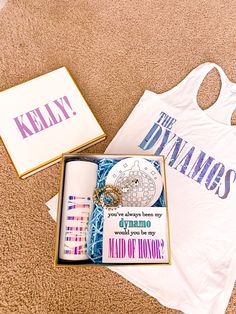 a white tank top and some other items on the floor next to a box that says kelly