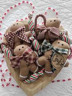 a heart shaped basket filled with lots of brown teddy bears sitting on top of a bed