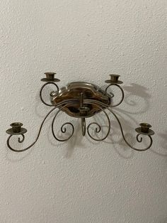 a wall mounted candle holder on the side of a white wall with three candles in it