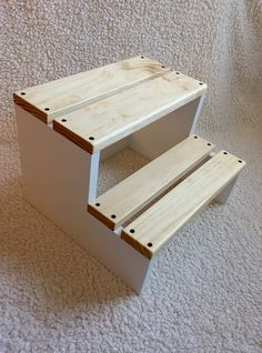 a wooden step stool sitting on top of a white carpet