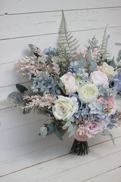 a bouquet of flowers sitting on top of a wooden table next to a white wall