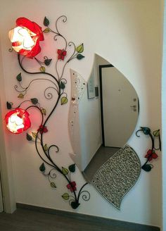 a mirror with flowers and leaves on it next to a wall mounted vanity light fixture