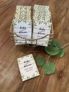 four baby bloom cards sitting on top of a wooden table next to a green plant