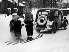 an old car is parked next to two skiers