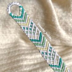 the beaded bracelet is made with white and green seed beads, which are attached to a silver clasp