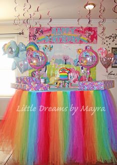 a birthday cake table with rainbow tulle skirt