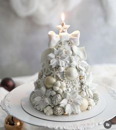 a decorated christmas tree on a plate with a lit candle in the middle and decorations around it