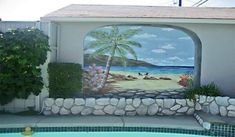 a mural on the side of a building next to a pool with a palm tree