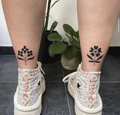 a pair of legs with tattoos on them and flowers painted on the side of their ankles