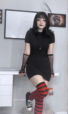 a woman in black dress and red striped stockings