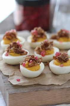 deviled eggs with meat on them sitting on a piece of paper