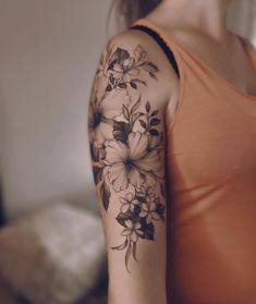 a woman's arm with flowers on it and a black ink tattoo that is in the shape of a flower