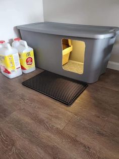 a dog house that is on the floor next to some cleaner bottles and detergent