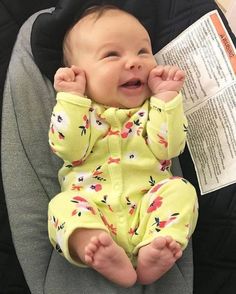 a baby sitting in a car seat with its hands on her face and mouth open