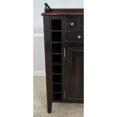 an antique wooden cabinet with glass doors and drawers on one side, in the middle of a carpeted room