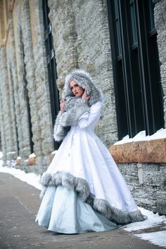 a woman in a long white dress and fur coat