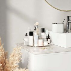 a bathroom counter topped with lots of different types of cosmetics and personal care items next to a mirror