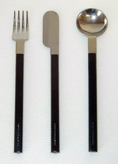 three forks, two spoons and one knife on a white surface with black handles