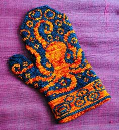 an orange and blue mitten sitting on top of a purple cloth covered tablecloth