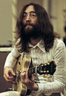 a man with long hair and glasses playing a guitar