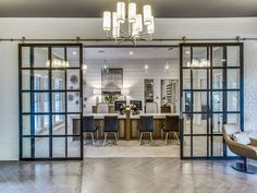 an open glass door leading to a dining room and living room with chandelier hanging from the ceiling