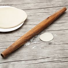 a wooden rolling pin sitting on top of a table next to a doughnut shell