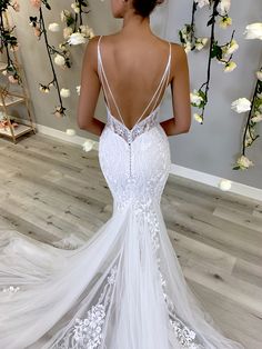 a woman in a white wedding dress looking back at the camera with flowers behind her