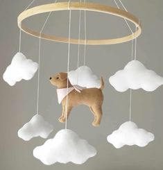 a toy dog is hanging from a wooden mobile with clouds in the sky behind it