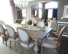 a dining room table with white chairs and chandelier