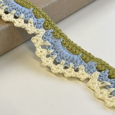 a crocheted ribbon is laying on top of a box