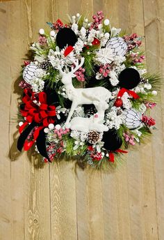 a christmas wreath on the floor with deer and pineconis in red, white and black