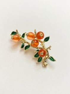 "Great brooch with orange beads for each piece of fruit.  Can be oranges, persimmon, tangerines, etc.  Great gift! Approximately 2-1/4\" long by 1-1/8\" wide. Not intended for children ages 13 and under.   Also, for many items we can accommodate large orders, so please send us a message." Orange Fruit Design Jewelry Gift, Persimmon Jewelry, Orange Fruit Jewelry, Tangerine Fruit, Formal Orange Brooch Jewelry, Luxury Elegant Orange Brooches, Vintage Orange Brooches For Gifts, Unique Orange Flower-shaped Jewelry, Orange Accessories