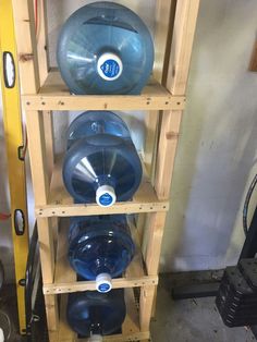 several large blue water bottles are stacked on wooden shelves