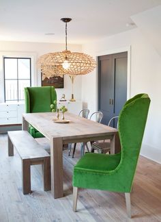 a dining room table with green chairs and a chandelier hanging from the ceiling