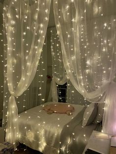 a bed with white curtains and lights on it