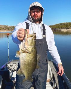 a man in overalls holding a fish on a boat