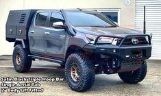 a gray truck parked in front of a building with the words, satin black triple hoop bar on it