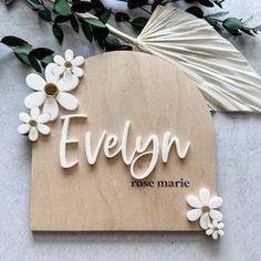 the name evelyn made out of wood with flowers and leaves around it on a table