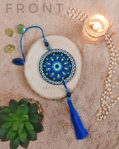 a blue and white beaded necklace sitting on top of a table next to a potted plant