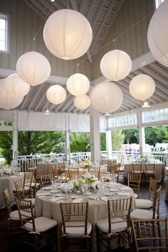 a room filled with lots of tables covered in white paper lanterns