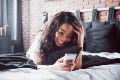 a woman laying in bed looking at her cell phone