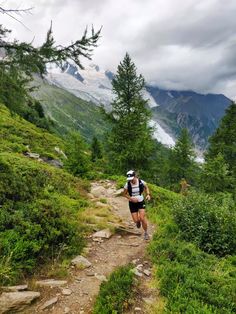 a man running down a trail in the mountains