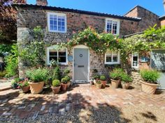 a brick house with potted plants in the front yard